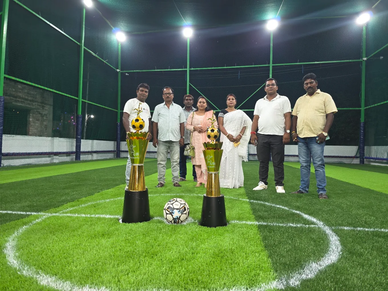 Tournament trophies displayed on the turf with guests