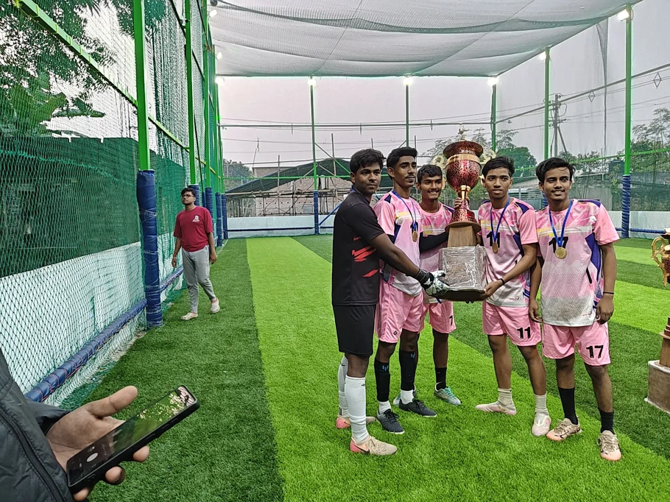 Pink football team celebrating with a trophy